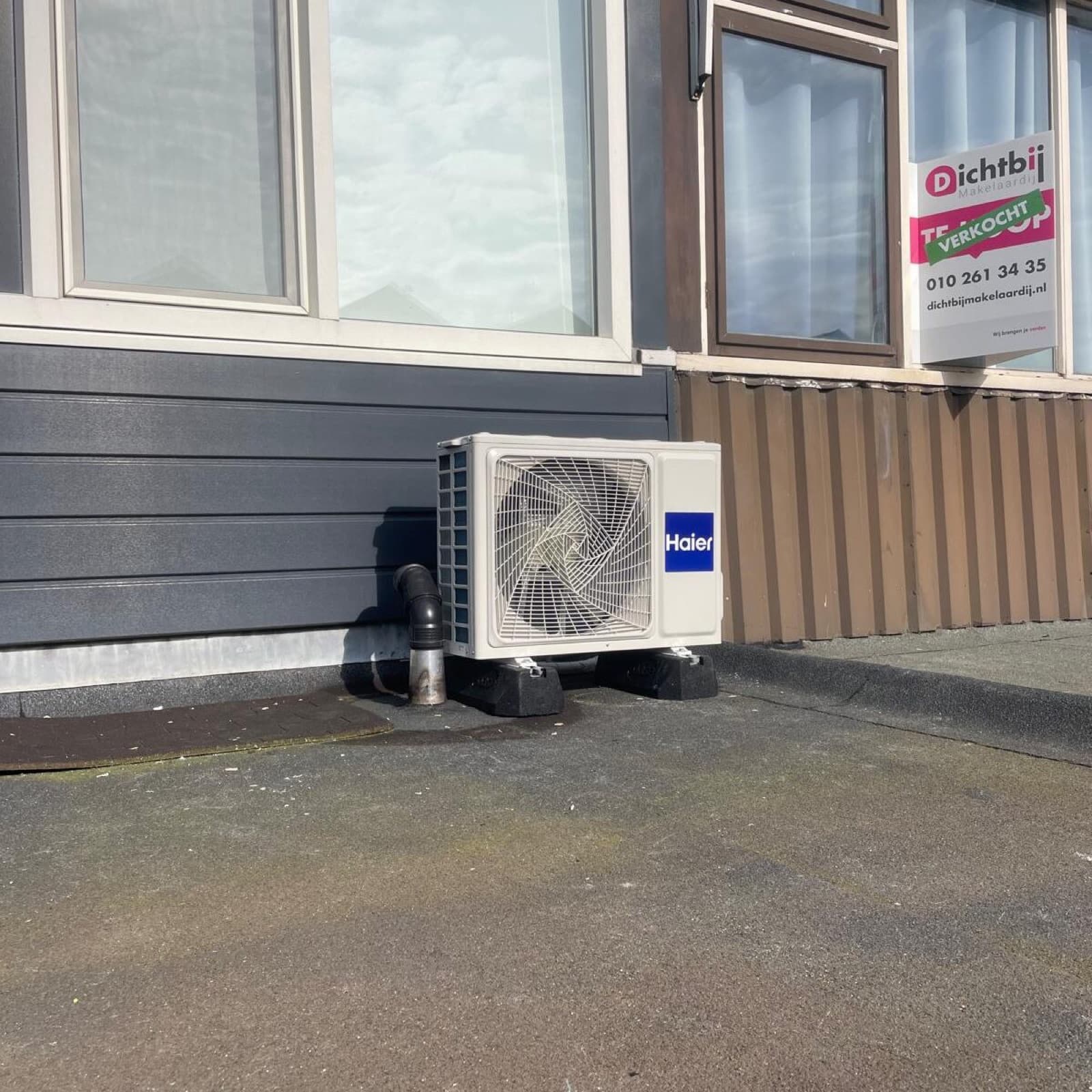 Airco buitenunit op de grond naast een woning