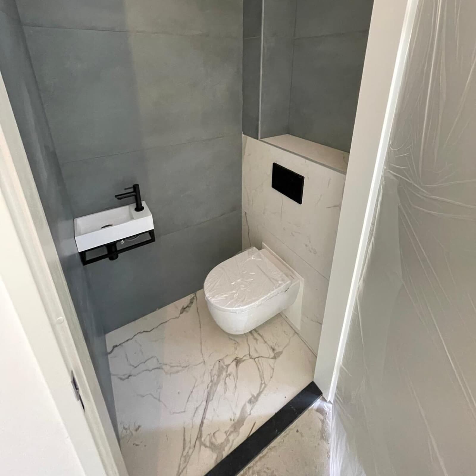 Toiletruimte met hangend toilet en zwarte fonteinkraan